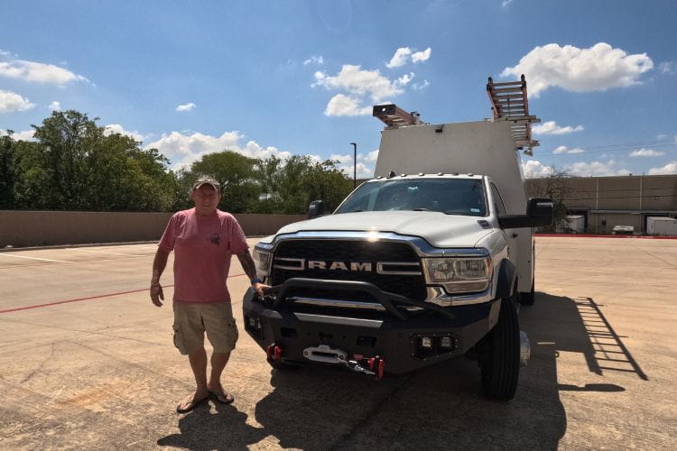Warn front bumper with Baja grille guard installed on a 2019-2026 Dodge Ram 4500 parked outdoors with a man standing beside it.