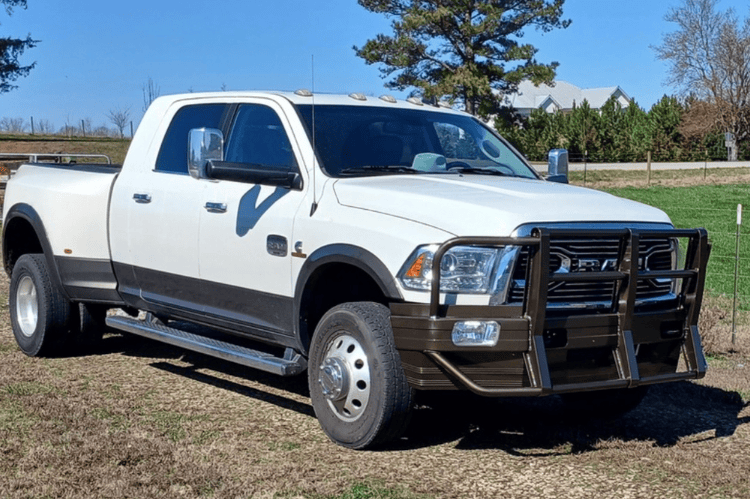 Ali Arc Classic front bumper for 2010-2018 Dodge Ram 2500 and 3500 trucks, featuring round fog light cut outs and rake style on a grassy field.