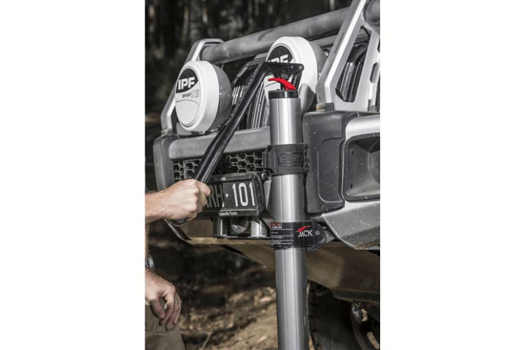 ARB hydraulic jack lifting a vehicle on uneven terrain, showing its rugged aluminum build and smooth hydraulic action.