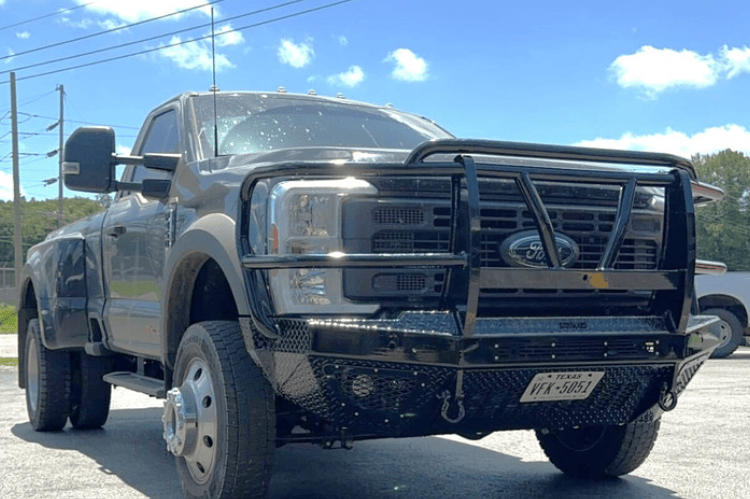 Bodyguard T2 Extreme front bumper with grille guard for Ford Super Duty F450/F550, texture black with parking sensor cutouts, camera harness, and winch mount skid plate.