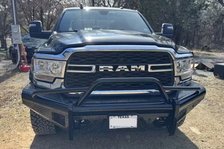 Fab Fours Black Steel Pre-Runner Guard front bumper for 2019–2024 Dodge Ram 2500 and 3500 HD (new body style), heavy-duty off-road steel bumper with integrated grille guard on a dirt road.