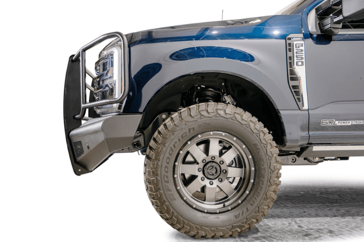 Fab Fours FS23-Q5960-1 Black Steel Elite Full Guard Front Bumper installed on a 2023 Ford F-250 Super Duty, featuring a matte black powder-coated finish, full grille guard, sensor compatibility, and mounts for 3x3 LED cube lights.