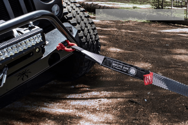 Tow strap attached to a vehicle's hitch on a dirt road