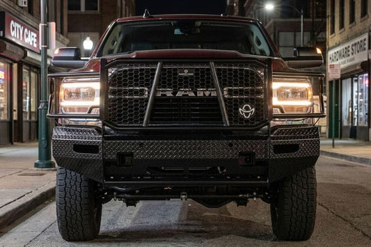 Front view of a Ranch Hand FSD191BL1C Summit front bumper with sensor compatibility for 2019–2024 Ram 2500 and 3500 trucks on a city street at night.