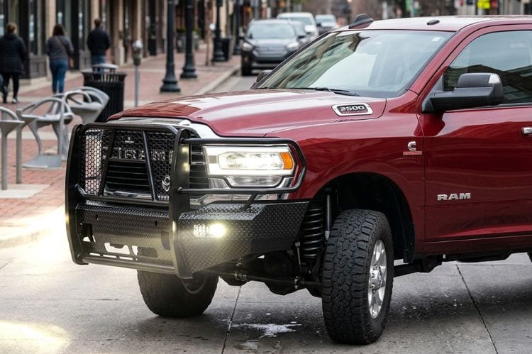 Side view of Ranch Hand FSD191BL1C Summit front bumper with sensor compatibility for 2019–2024 Ram 2500 and 3500 trucks parked on a city street with pedestrians in the background