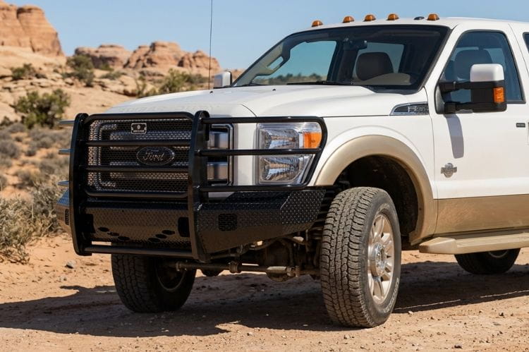 Side view of Ranch Hand FSF111BL1 front bumper for 2011–2016 Ford F250 and F350 Super Duty trucks in a desert landscape with rocky formations.