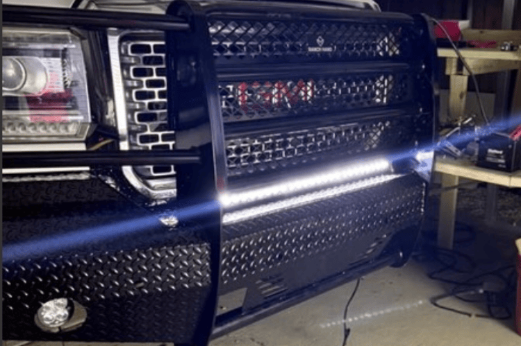 Close-up of a Ranch Hand Summit Series Front Bumper FSG151BL1 in Black for 2015-2019 GMC Sierra 2500HD and 3500HD trucks, in a workshop setting.