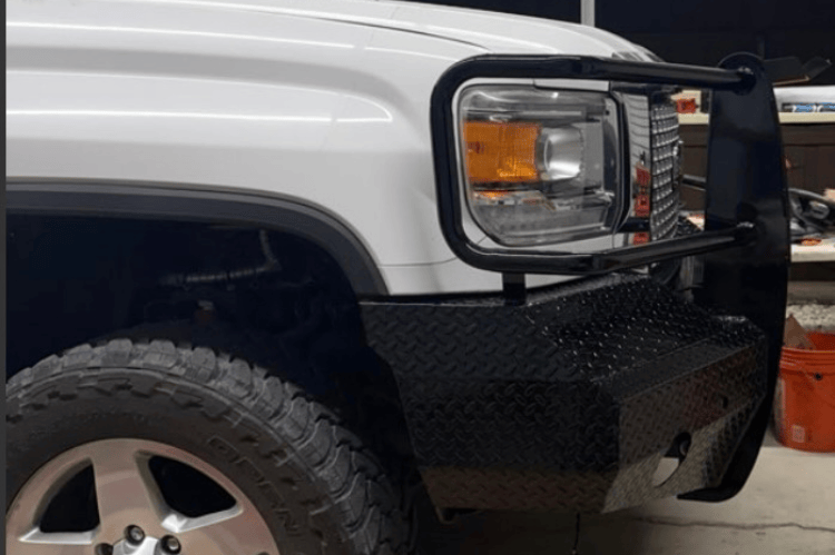 Side-view of a white truck with Ranch Hand Summit Series Front Bumper FSG151BL1 in Black for 2015-2019 GMC Sierra 2500HD and 3500HD trucks. in a garage setting.