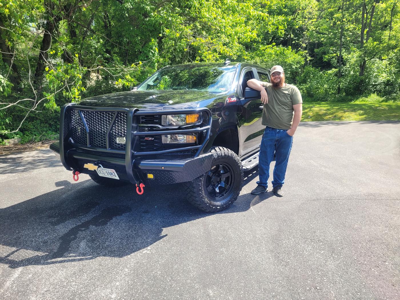 A customer leaning on his Chevy Silverado fitted with a black winch front bumper