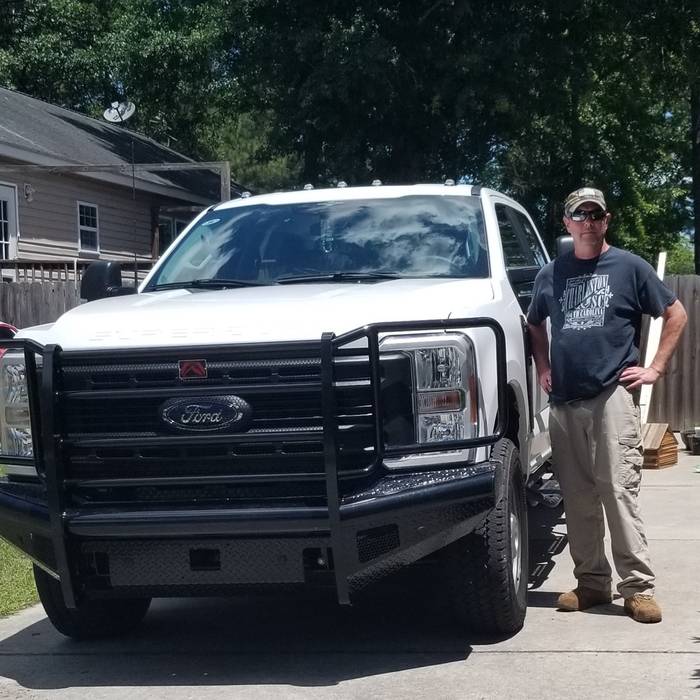 A customer beside his white Ford F-250 with a Ranch Hand front bumper