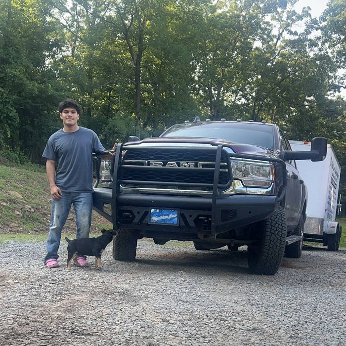 A young customer with his Ram and a black winch bumper, a small dog at his feet