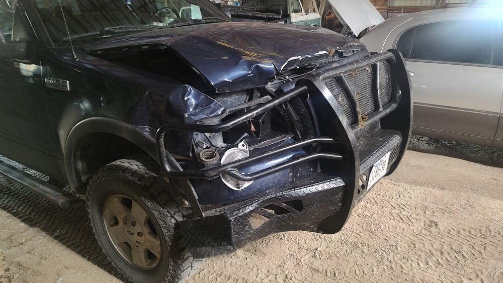 A 2004–2005 Ford F-150 with a Frontier Original front bumper after a deer strike; the hood is crumpled, the bumper held